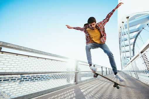 Skateboarding on sunny spring day - young man in casual clothing enjoying skateboarding