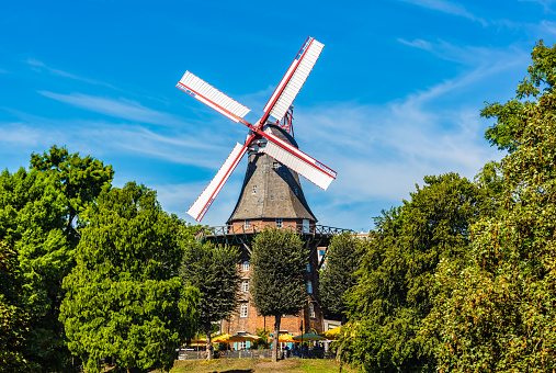 The sun sets behind an antique windmill in a composite image.