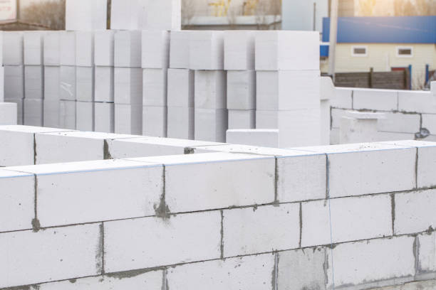 istock Piled cinder blocks at the construction site. Unfinished house wall made from white aerated autoclaved concrete blocks 1312350892