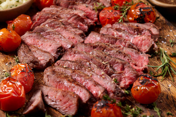 Medium Rare Flat Iron Steaks with Roasted Cherry Tomatoes Flat Iron Steaks with Roasted Cherry Tomatoes, Herb, Garlic Compound Butter and Peppercorn Au Jus flank steak stock pictures, royalty-free photos & images