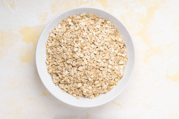 istock Oat flakes in a white plate on a yellow cement background 1312353074