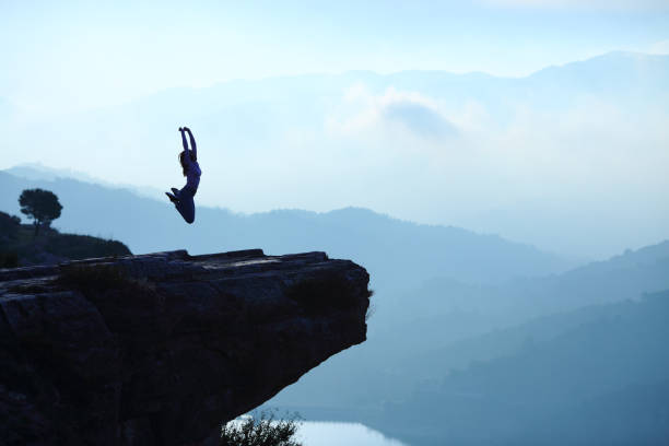 istock Woman jumping in a cliff on blue landscape 1312354159
