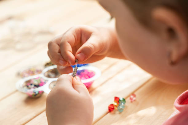 istock A little girl is engaged in needlework, making jewelry with her own hands, stringing multi-colored beads on a thread 1312356537