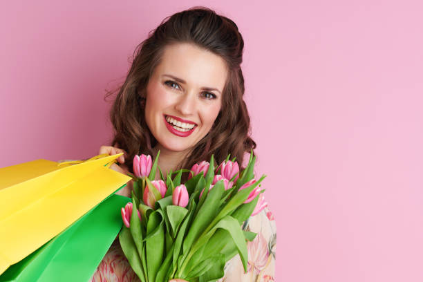 porträt der lächelnden stilvollen frau in blumenkleid auf rosa - single flower flash stock-fotos und bilder