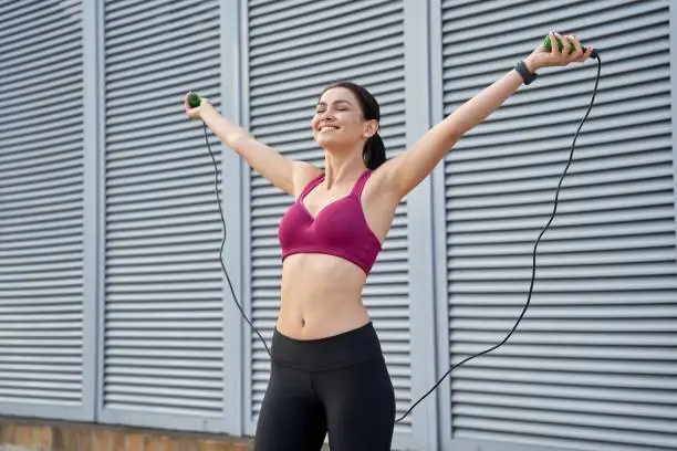 Smiling pretty lady enjoying a skipping rope workout outdoor. Sport concept. Copy space