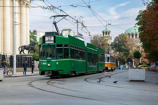 Sofia, Bulgaria - 26th September, 2019: Trams (Schindler Be4/6S on a first plan) driving in Sofia city center. On the back of the trams we see the Alexander Nevsky Cathedral.