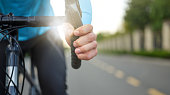 Close up of hand on handlebar. Male cyclist cycling, riding a bike in park on a daytime