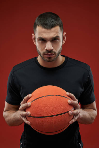 istock Seriously basketball player holding with both hands a orange ball 1312359558