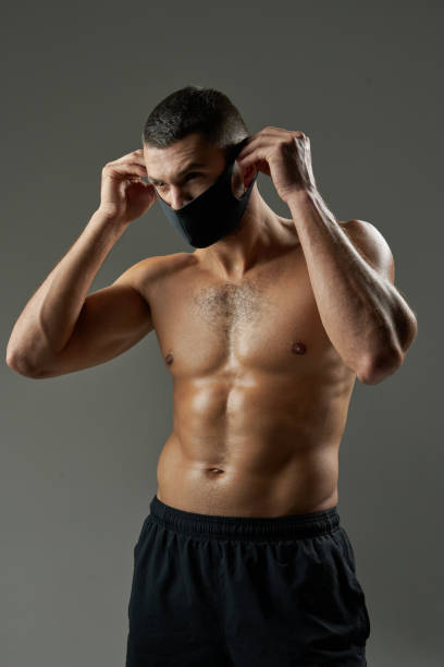 istock Adorable strong athlete in protective mask posing at the camera on grey background of a studio 1312359725