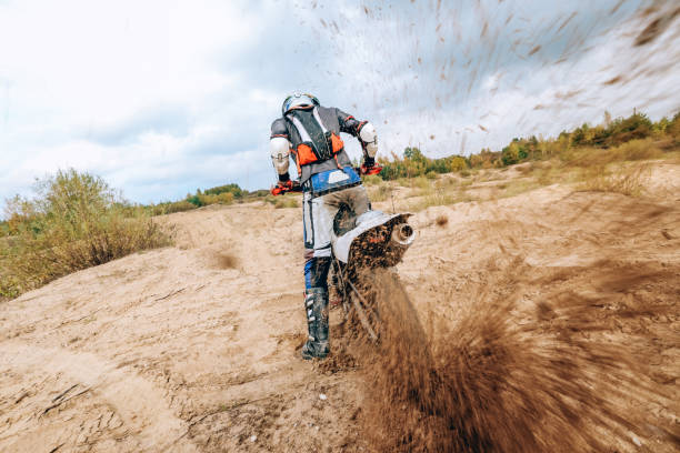 Male portrait of motocross enduro rider outdoors. Sports concept for motorsport on sports track. Professional biker with helmet and stunt motorcycle. Man with protective sportswear. Mud from wheels retrato masculino del piloto de enduro de motocross al aire libre. concepto deportivo para el automovilismo en pista deportiva. motociclista profesional con casco y moto de acrobacias. hombre con ropa deportiva protectora. barro de las ruedas