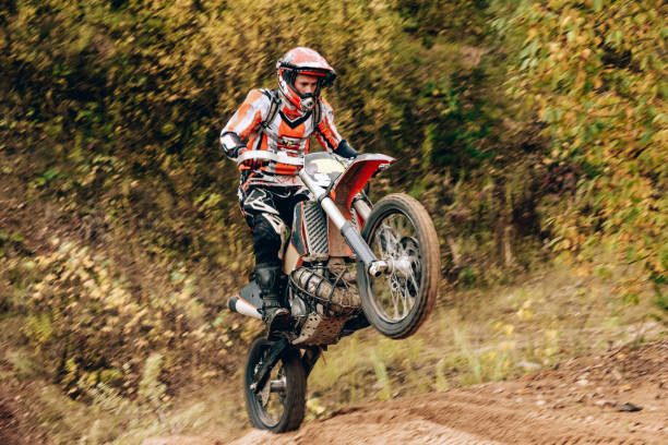 retrato masculino del piloto de enduro de motocross al aire libre. concepto deportivo para el automovilismo en pista deportiva. motociclista profesional con casco y moto de acrobacias. hombre con ropa deportiva protectora - action off road vehicle motocross cycle fotografías e imágenes de stock