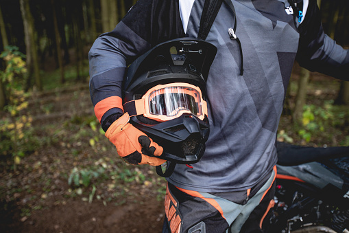 Male portrait of motocross enduro rider outdoors. Sports concept for motorsport on sports track. Professional biker with helmet and stunt motorcycle. Man with protective sportswear.