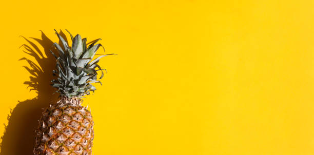 istock Ripe pineapple on a yellow background with deep shadow on a bright sunny day with copy space. Banner. Summer concept, vacation concept. Top view 1312365963