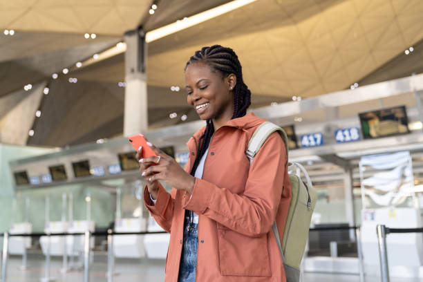 istock Happy afro woman check smartphone message after first flight after covid end and arrival in airport 1312366983