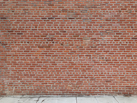 This is a photograph of an old brick wall and sidewalk