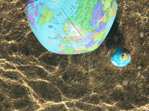 istock Rising Warm Ocean Concept - Globe Balls Floating in Sea 1312376103