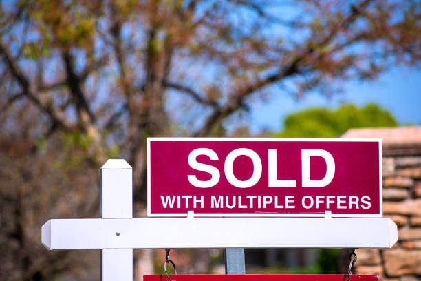 SOLD With Multiple Offers real estate sign near purchased house. SOLD With Multiple Offers real estate sign near purchased house indicates hot seller's market in the desired neighborhood. Blurred outdoor background. Bidding war concept. auction photos stock pictures, royalty-free photos & images