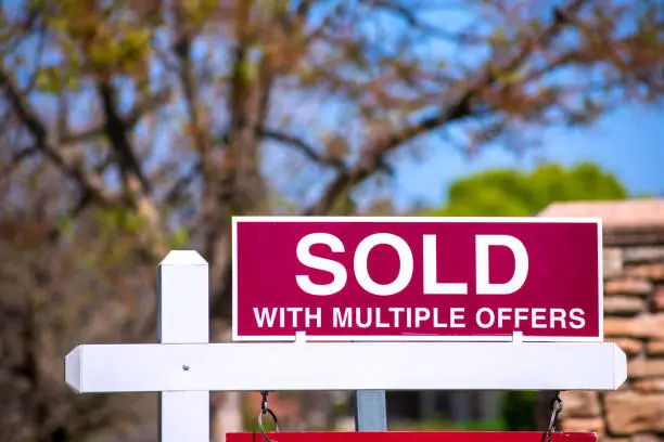Photo of SOLD With Multiple Offers real estate sign near purchased house.