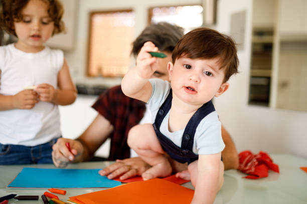 istock Cute little boy crawling on a table, holding a crayon 1312382263