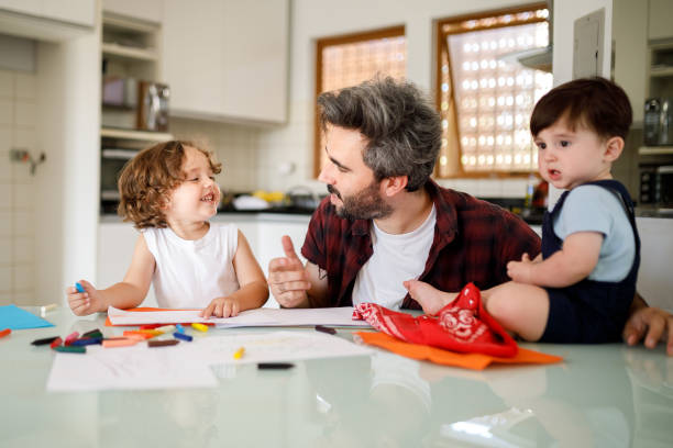 istock Father and sons having fun making mother's day card 1312382289