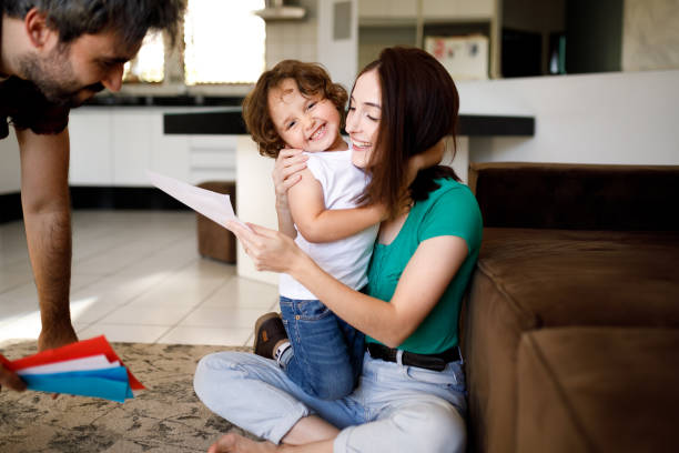 istock Mother sitting on floor, reading a greeting card and hugging her smiling son 1312382297
