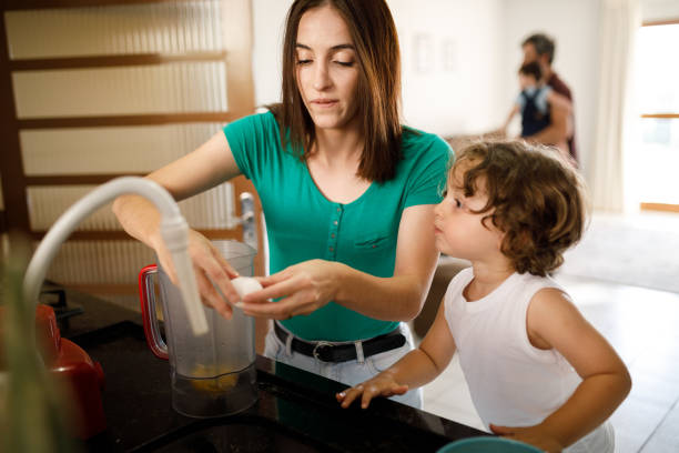istock Young woman cracking an egg with her son in the kitchen 1312382339