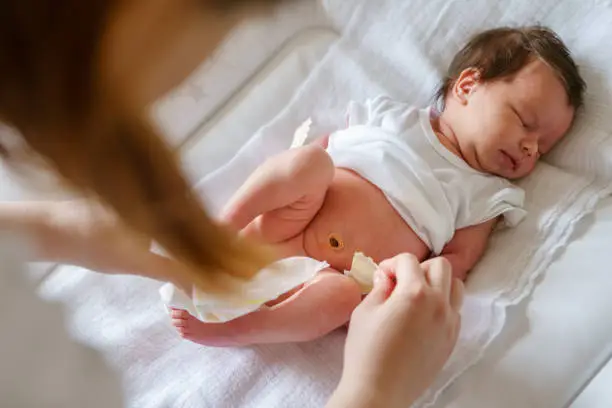 Photo of Top view on caucasian baby sleep while her mother is changing diapers and clothes newborn lying on the bed at home - parenting childhood new life and growing up concept