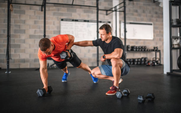 istock Coach Supervising Athlete as He Does Renegade Row Push-Ups 1312385630