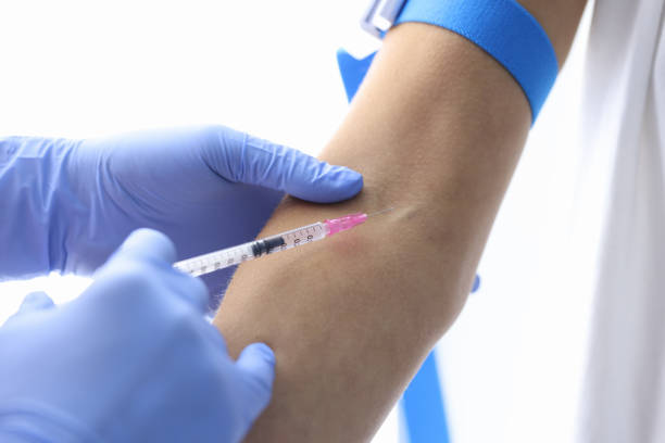 istock Gloved doctor injects patient into vein closeup 1312386656