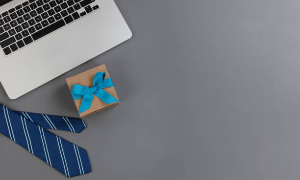 Fathers day concept with blue dress tie plus laptop computer and giftbox on a gray background stock photo