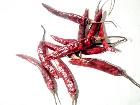 A closeup of dry chili peppers isolated on a white surface.