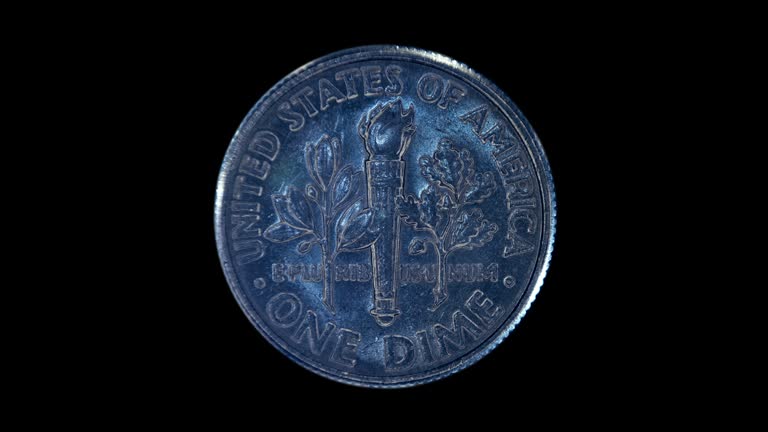 On a black background, one dime coin is glitters in the rays of light