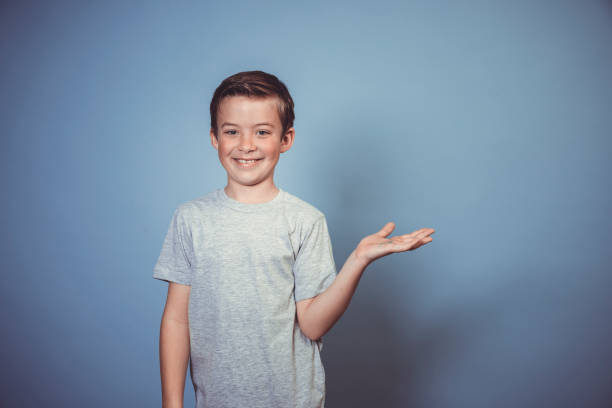 istock cool, young boy with grey t-shirt is posing in front of blue background 1312398433