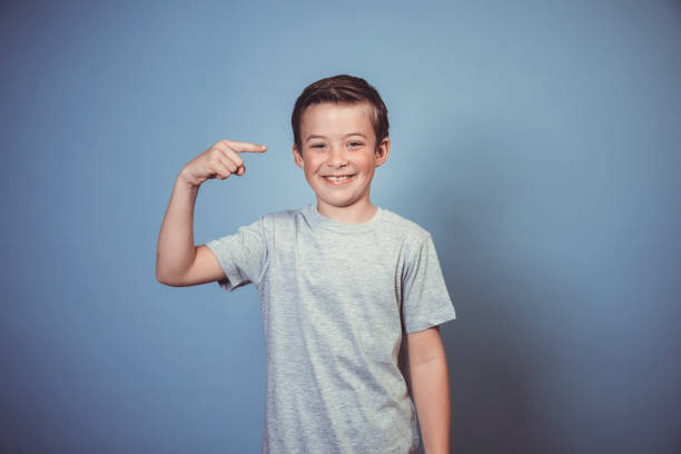 istock cool, young boy with grey t-shirt is posing in front of blue background 1312398452