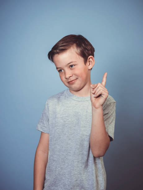 istock cool, young boy with grey t-shirt is posing in front of blue background 1312398513