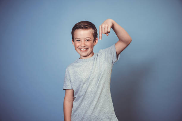cool, young boy with grey t-shirt is posing in front of blue background