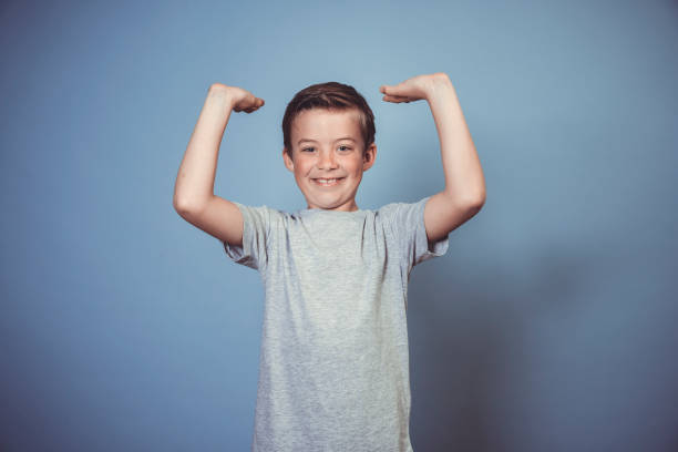 istock cool, young boy with grey t-shirt is posing in front of blue background 1312398536