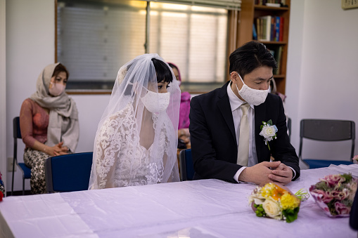 Indonesian woman and Japanese man having Islam style wedding ceremony and wedding party in Tokyo, Japan. Bride and groom, and participants are wearing face mask in most of the time to protect against coronavirus.
