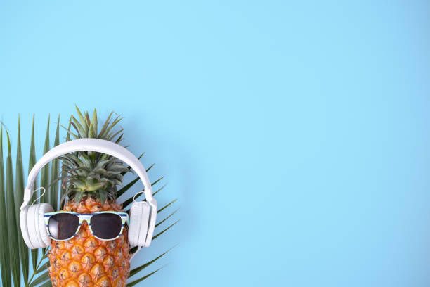 istock Funny pineapple wearing white headphone isolated on blue background. 1312400909