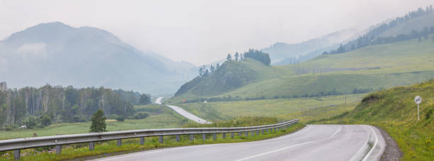 istock The road passes through a mountain valley, rainy weather, panoramic view 1312403883