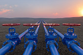 Öl- oder Gastransport mit blauen Gas- oder Rohrleitungsventilen auf Boden und Sonnenaufgang Hintergrund