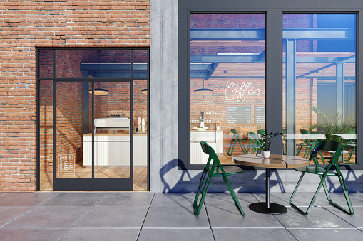 Escaparate de cafetería con mesa, sillas verdes frente a la tienda y fondo de pared de ladrillo. photo