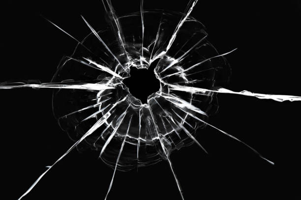istock Cracks in the window from a shot from a weapon. Damaged window glass. White cracks on a black background 1312406557