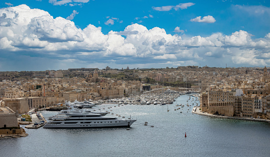 Valletta, Malta. Grand harbour, luxury yachts marina aerial view from Upper Barrakka Gardens, cloudy blue sky