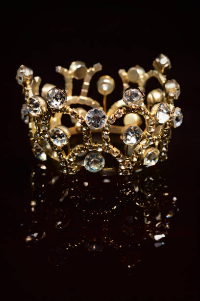 istock Gold crown with shiny stones on a black background. 1312411135