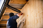 Roofer builder worker finishing folding a metal gutter