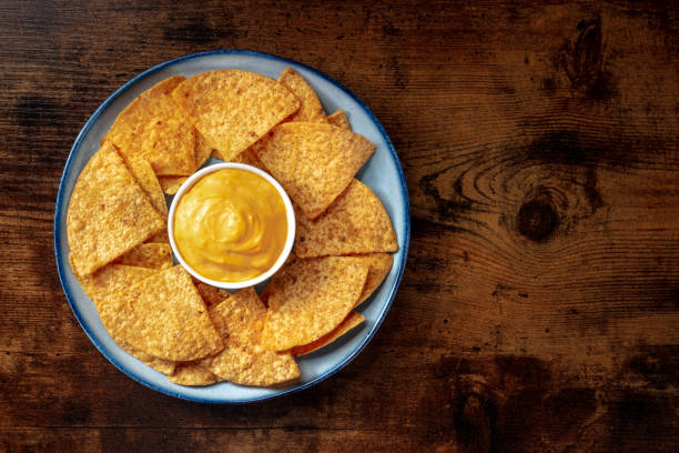 istock Nacho chips with a Cheddar cheese dip, shot from the top on a wooden background 1312414160