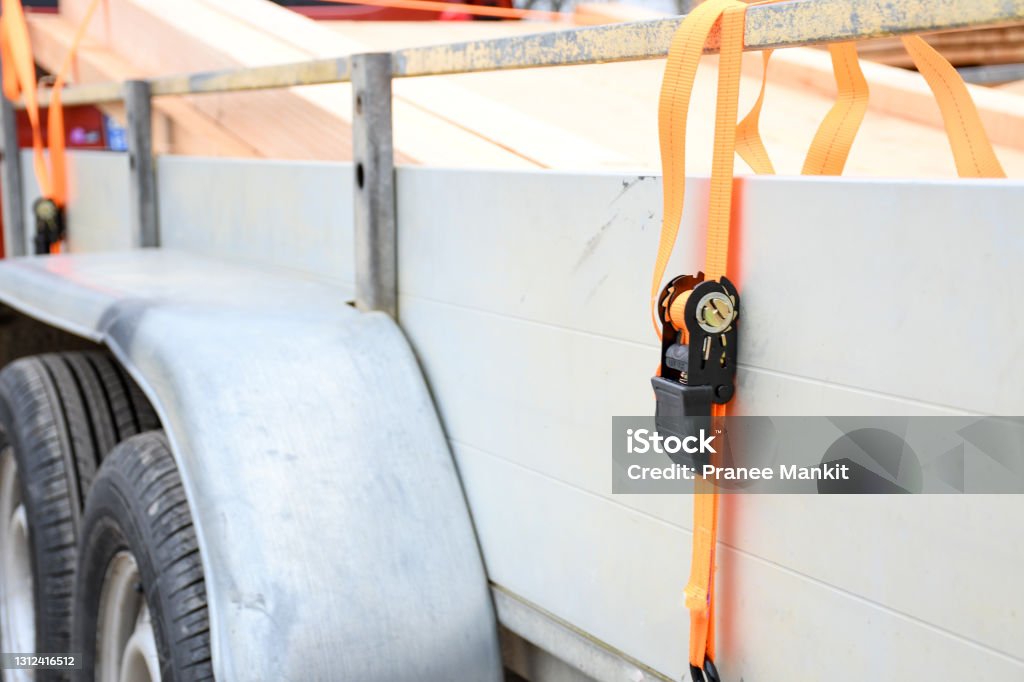 Trailer strop or strap in orange nylon and metal, object helping for holding stuff , storage and transport for safty and security. Tying Stock Photo