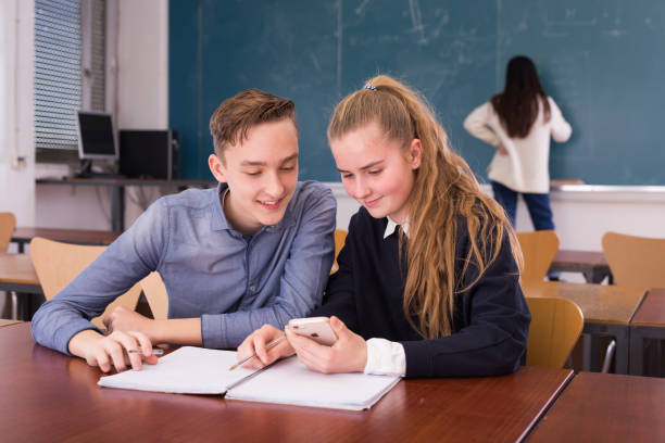 istock Young guy and girl students doing lesson in classroom 1312416665