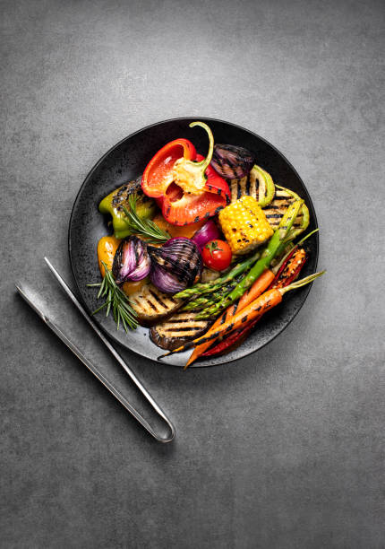 verduras a la parrilla servidas en un plato con pinzas bbq - food dining cooking multi colored fotografías e imágenes de stock